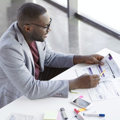 top-view-of-dark-skinned-african-male-copywriter-or-enterpreneur-looks-attentively-at-documents-stu.jpg